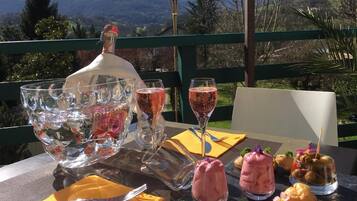 A table set outdoors with a bottle of sparkling wine, glasses, and a variety of desserts.