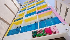 A multi-story hotel with a distinctive facade featuring alternating yellow and blue balconies. - Hotel 99 (Taichung)