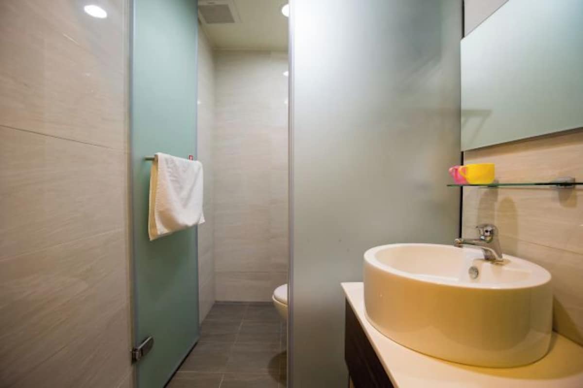 A modern bathroom with a round sink, a glass shower enclosure, and a toilet.