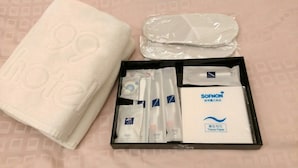A hotel room with a neatly folded white towel, a set of toiletries including a toothbrush, toothpaste, and a tissue paper box. - Hotel 99 (Taichung)
