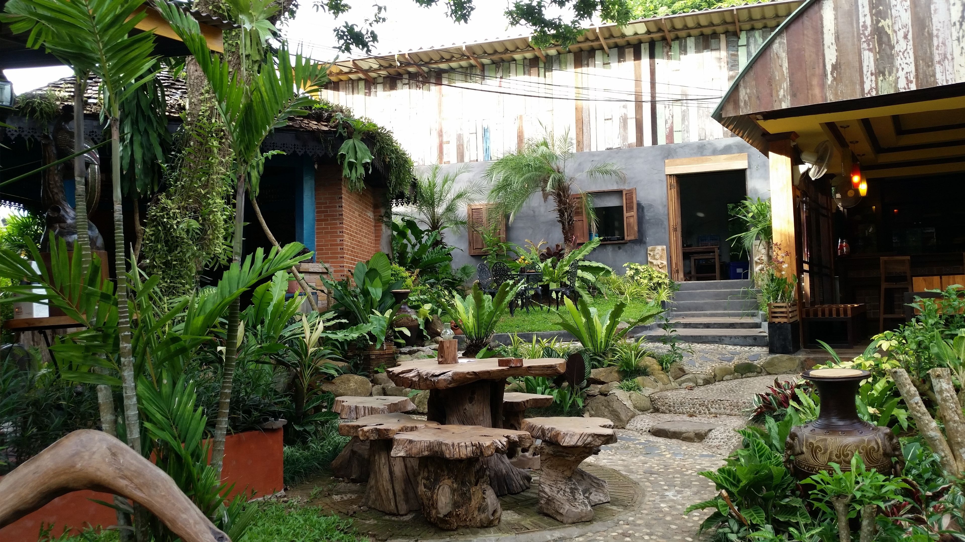 A courtyard with rustic wooden tables and a stone pathway.