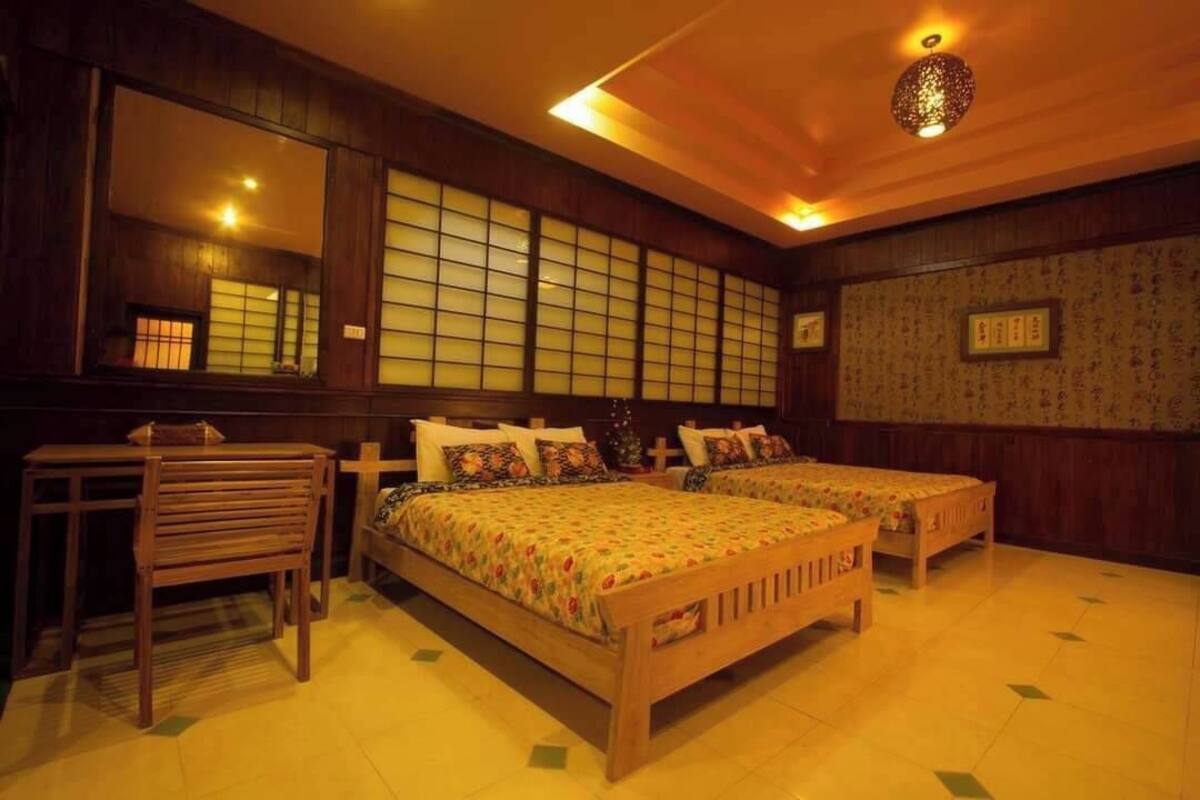 Una habitación tradicional japonesa con dos camas de madera, una silla de madera y un ventanal con diseño de cuadrícula.