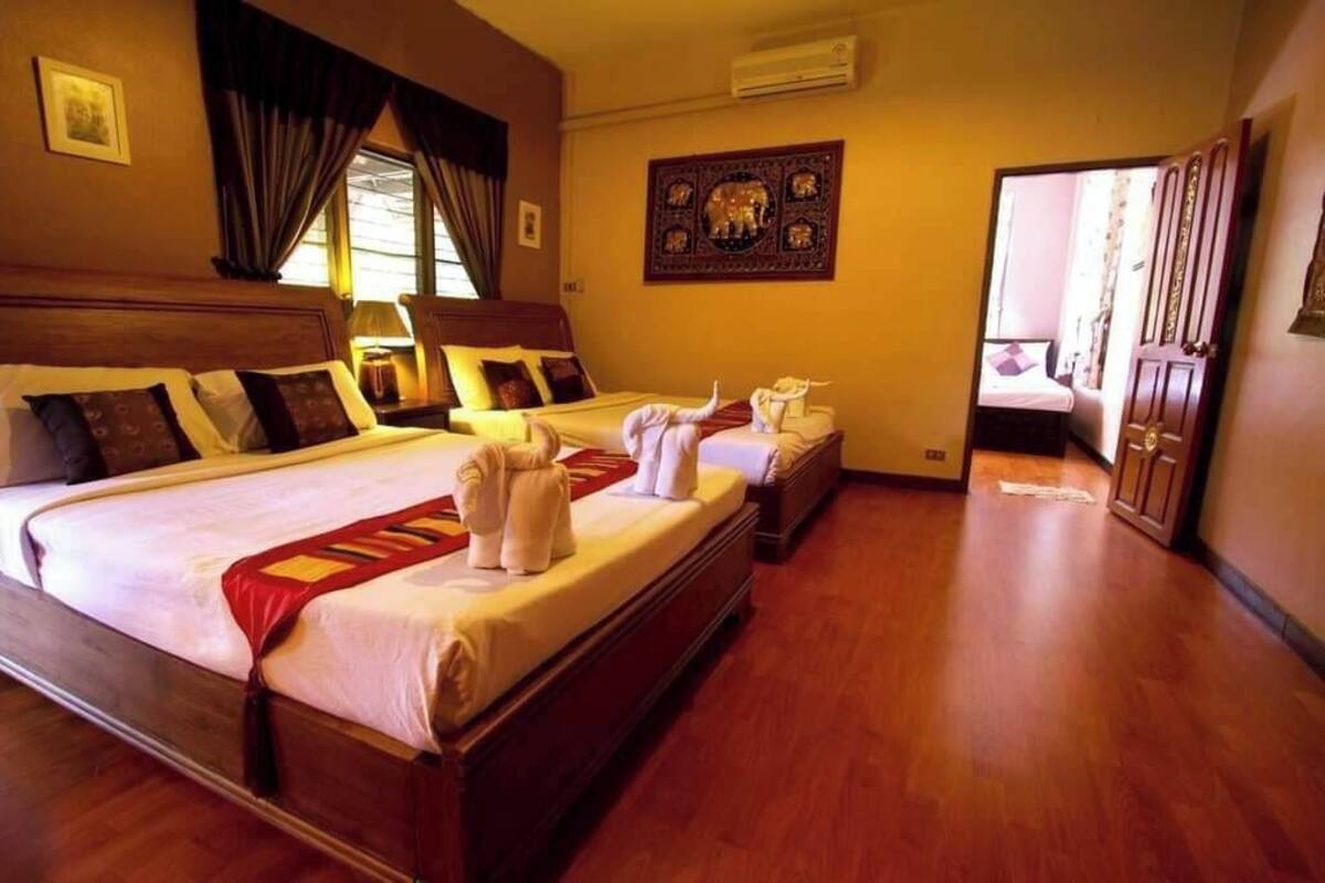 Habitación de hotel con dos camas, suelo de madera, un espejo grande y un cuadro colgado en la pared.
