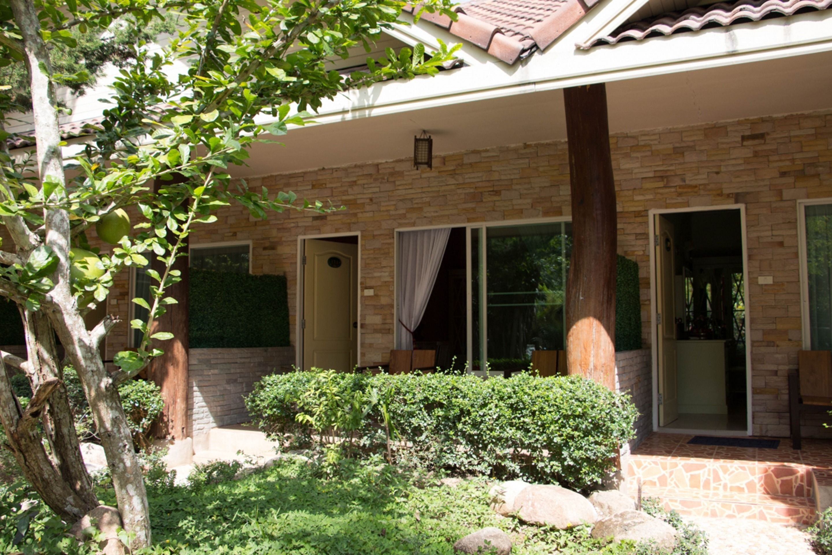 A house with a stone facade, large windows, and a covered porch area.