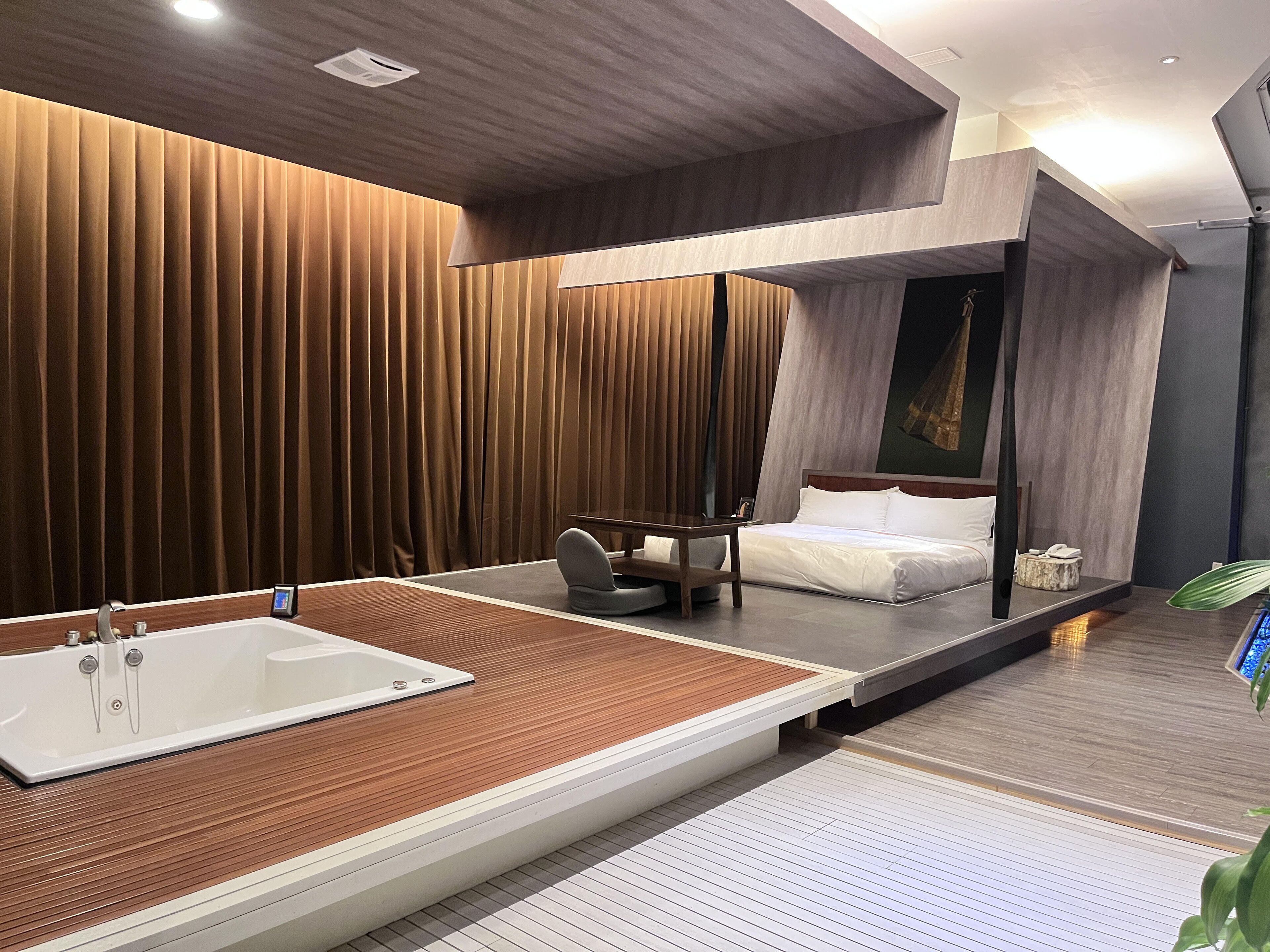 A modern hotel bathroom with a large bathtub, wooden paneling, and a separate shower area.