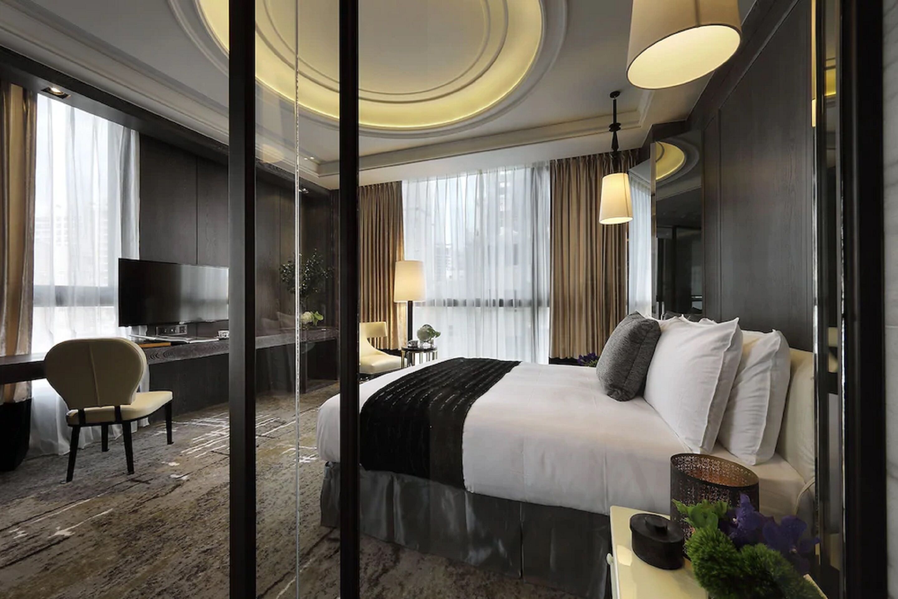 Una habitación de hotel moderna con una cama grande, un escritorio, una silla y un televisor.