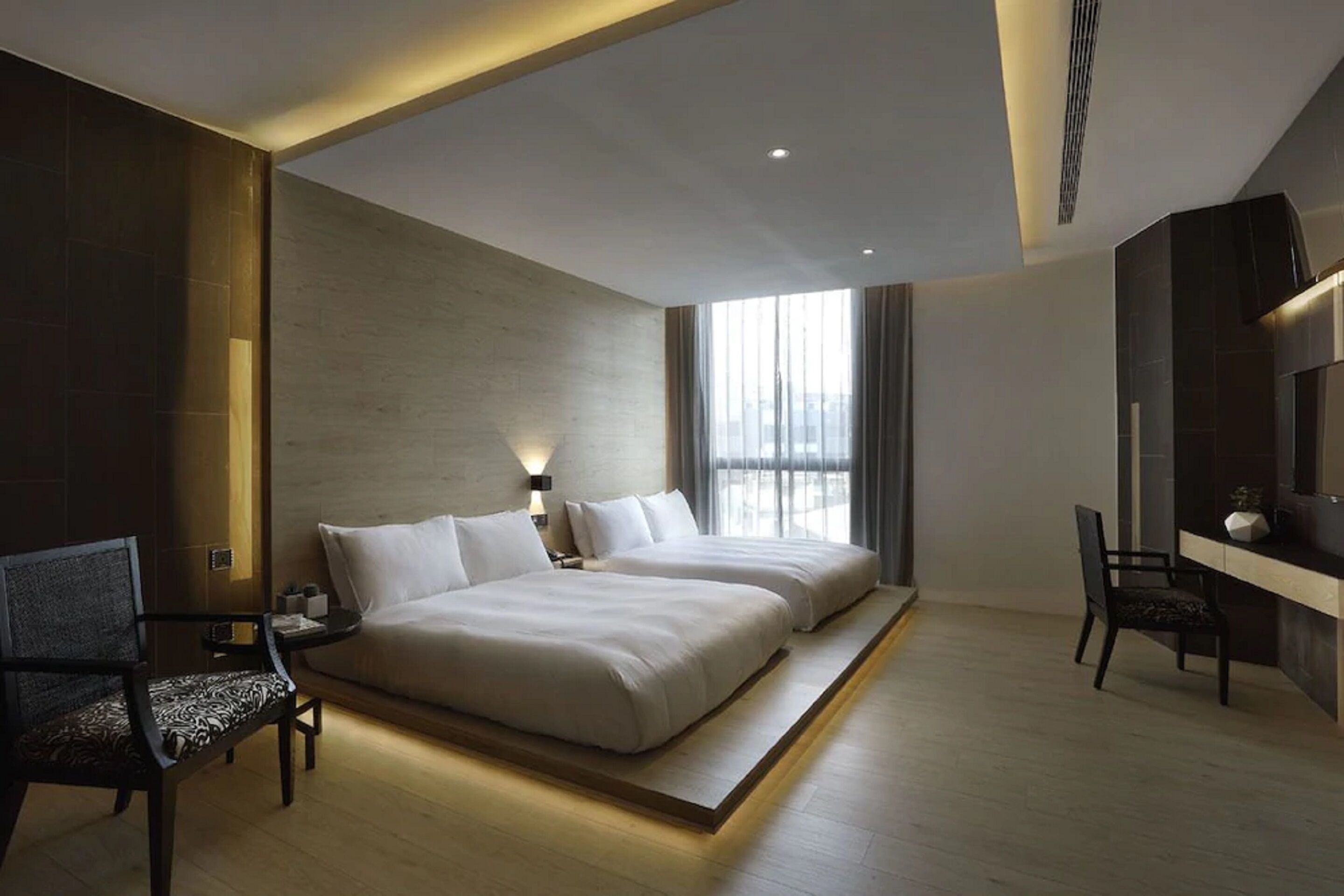 Una habitación de hotel moderna con una cama grande, un escritorio y una silla.