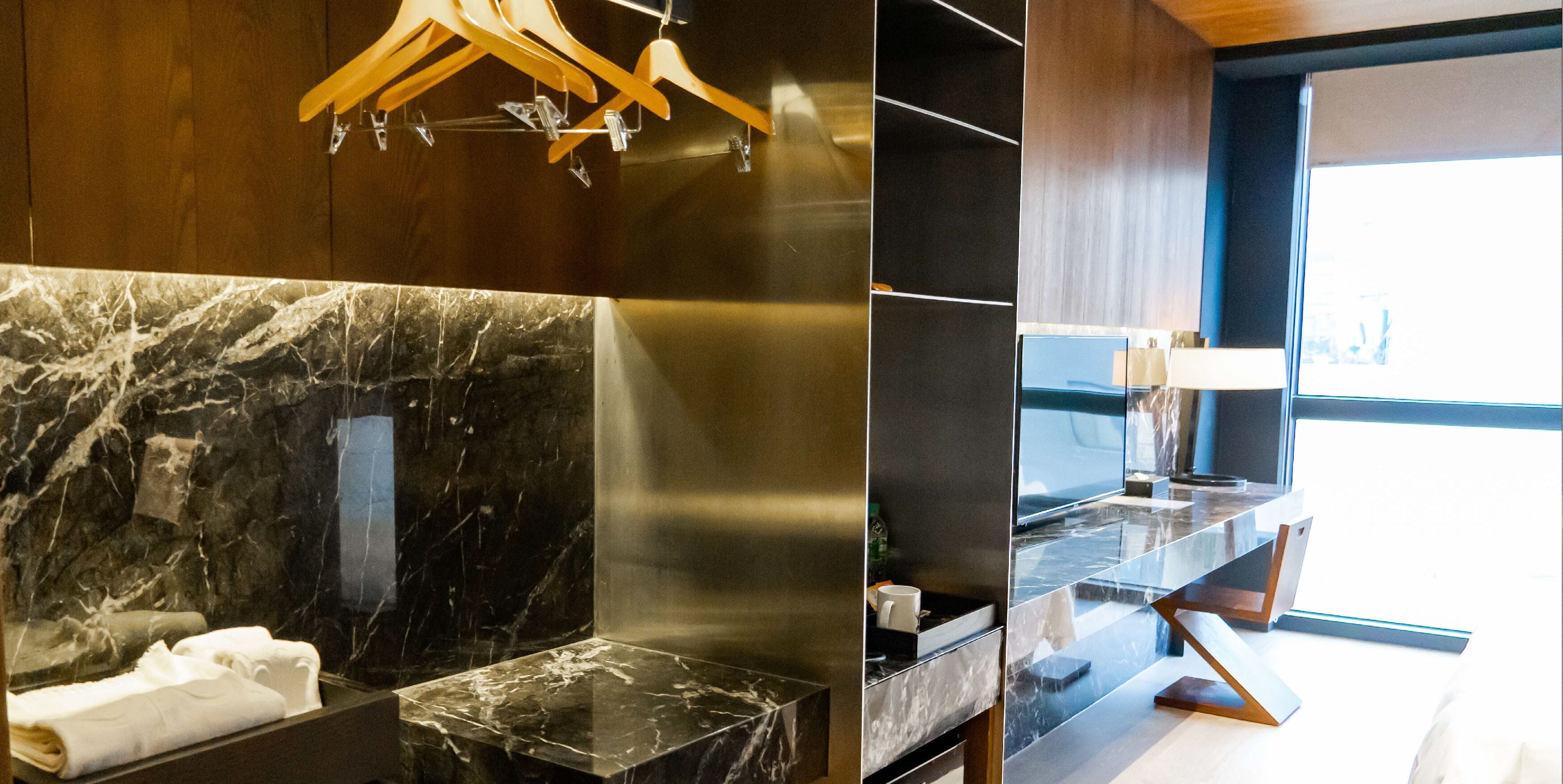 A modern bathroom with a marble countertop, a towel rack, and a mirror.