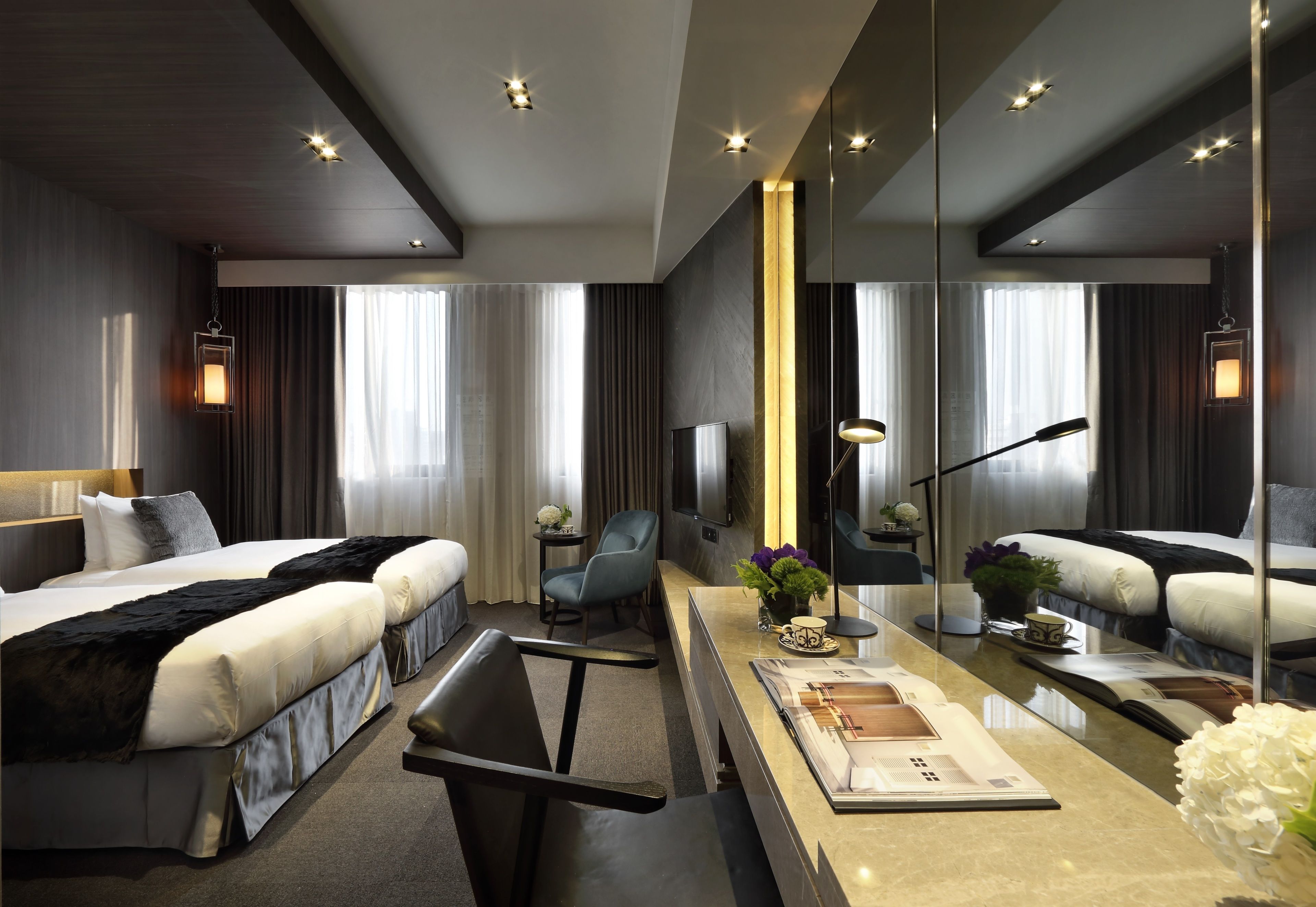 A modern hotel room with a large bed, a desk, a chair, a TV, and a mirror.