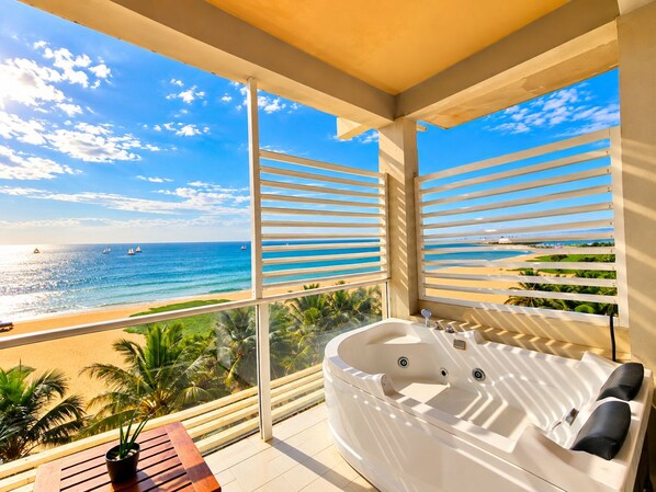 A balcony with a view of the beach and ocean, a jacuzzi, and a small table with a plant. - Beacon Beach Hotel (Negombo)