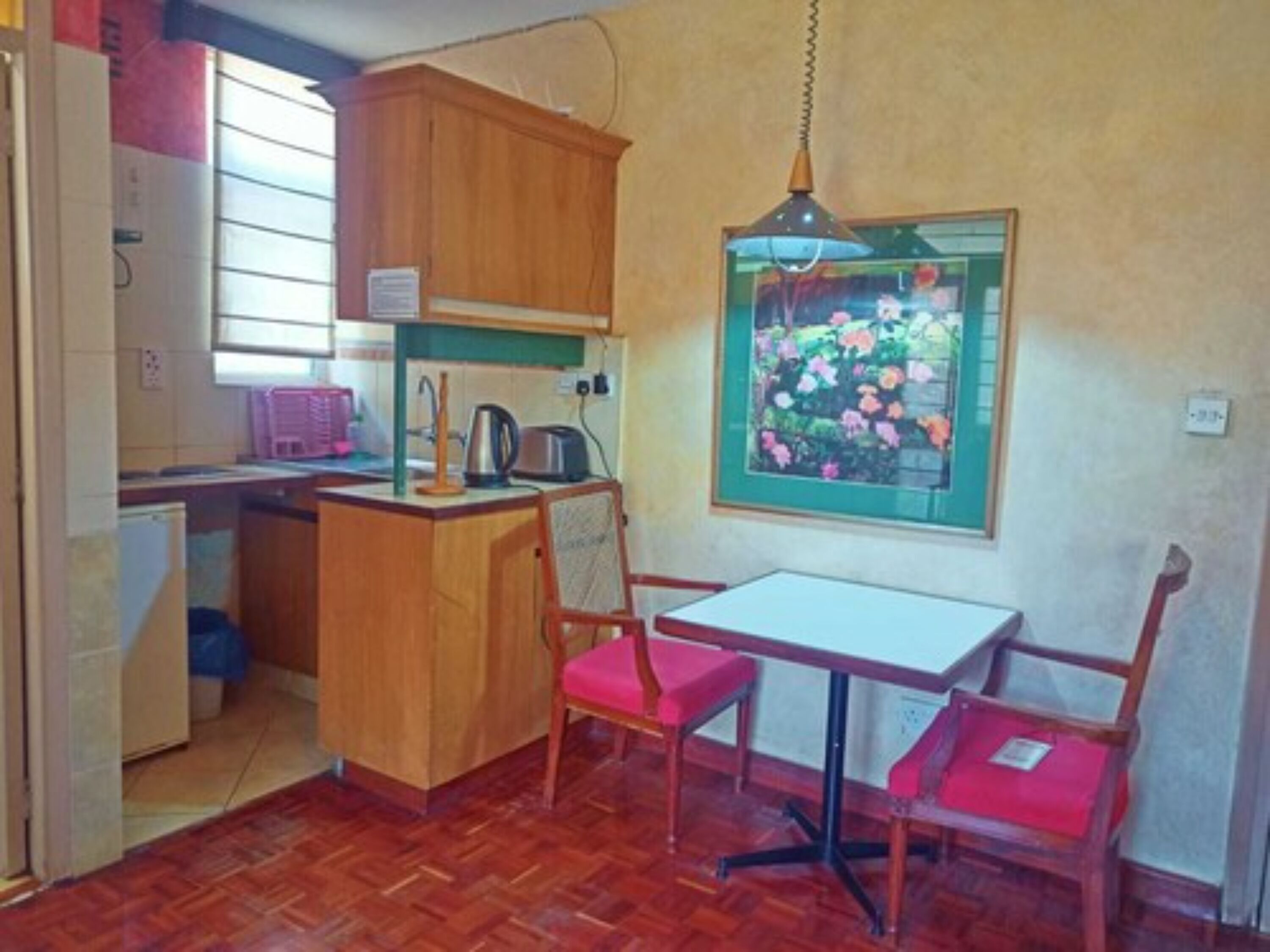 A compact kitchen with wooden cabinets, a small island, and a dining area with two chairs.