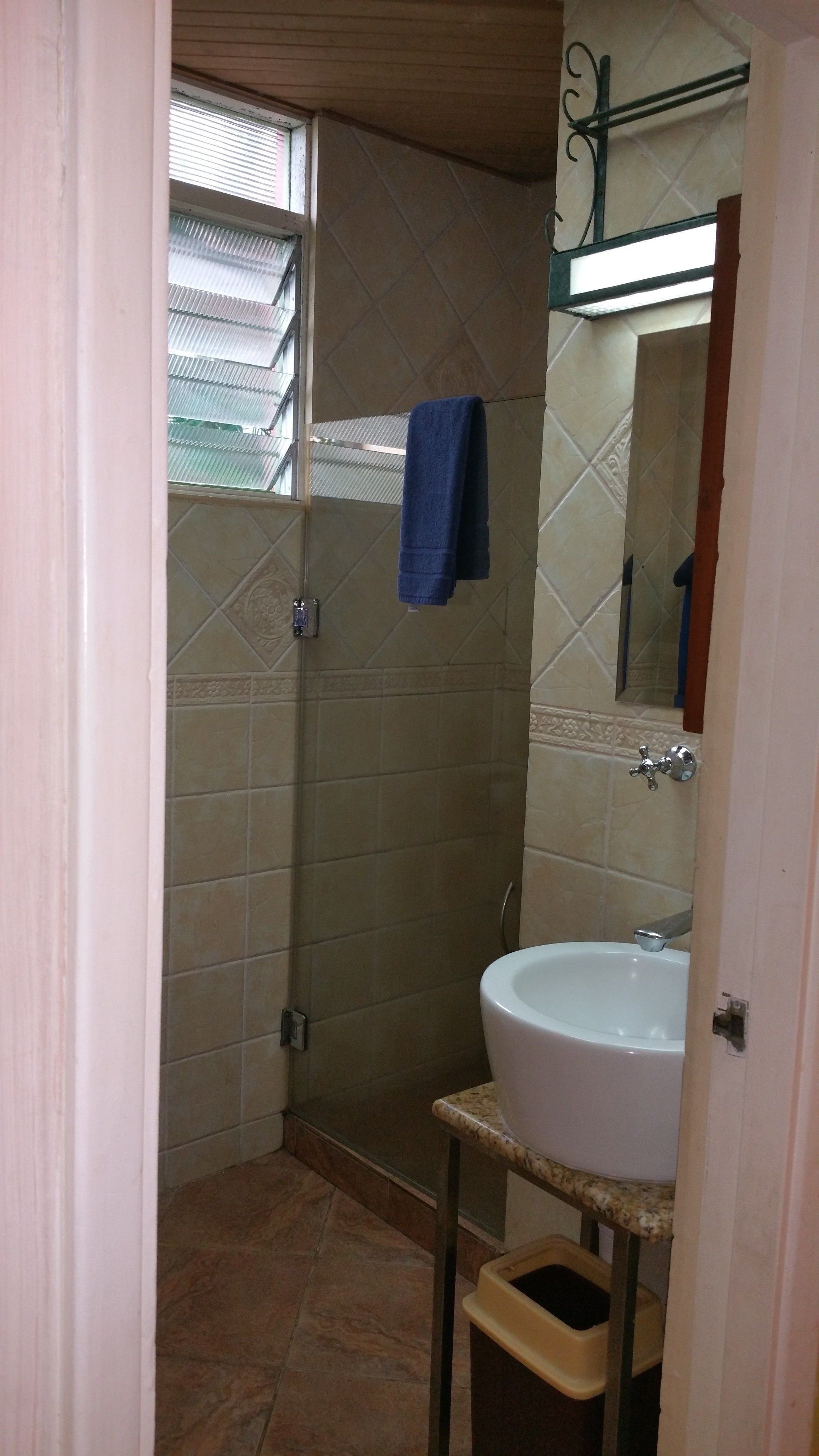 Une salle de bain avec une douche, un lavabo et une fenêtre équipée de stores.
