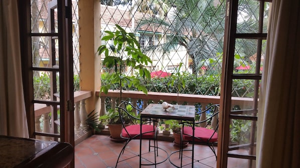 Un balcon avec une table et des chaises, entouré de plantes en pot.