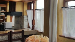 A wooden interior with a dining table, chairs, a vase of flowers, and a hanging light fixture. - Woodmere Serviced Apartments (Nairobi)