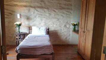 Relax in this charming room with a wooden bed, nightstand, and wardrobe, surrounded by natural textures and simple decor.