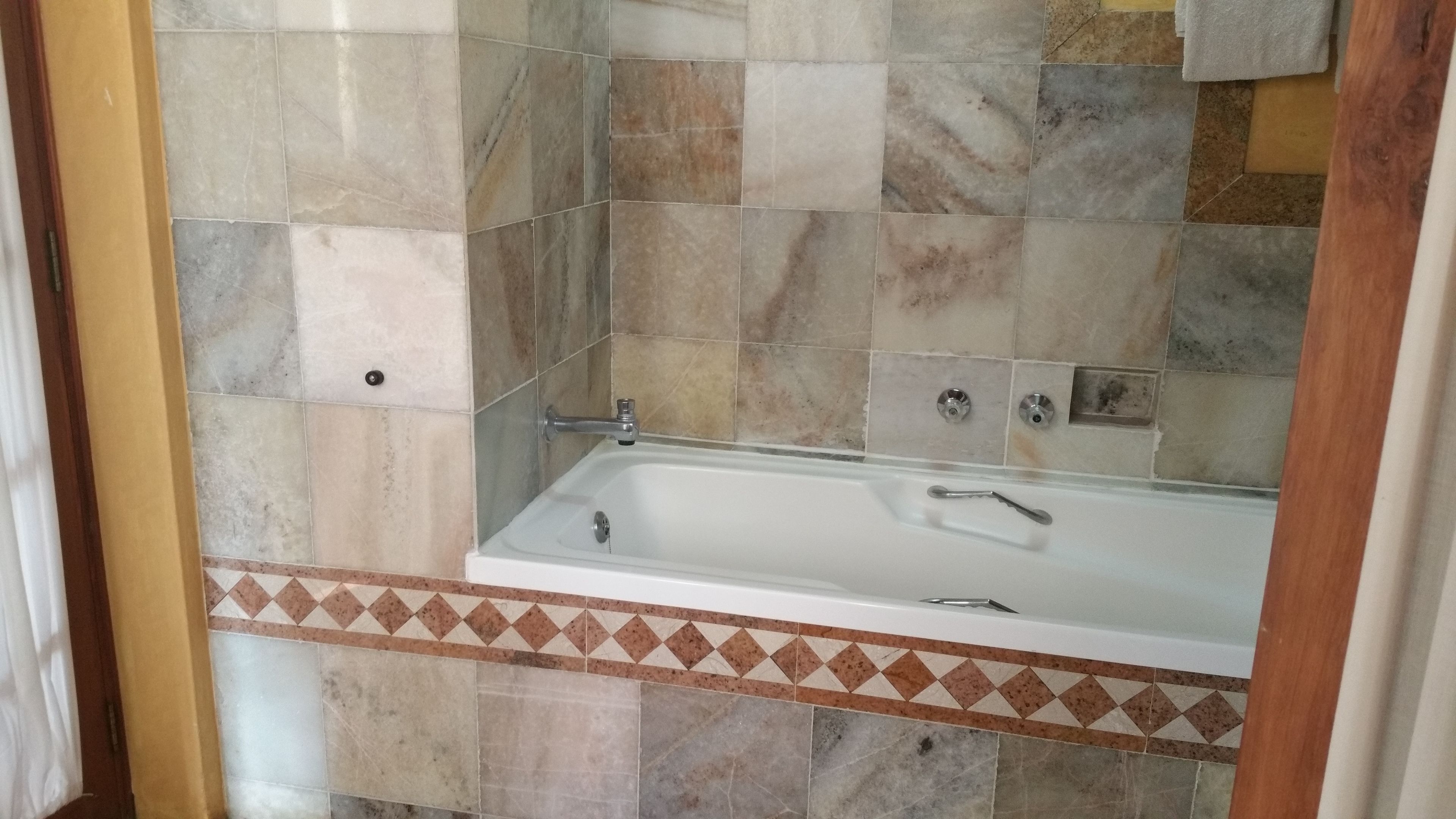 A bathroom with a bathtub, tiled walls, and a patterned border.