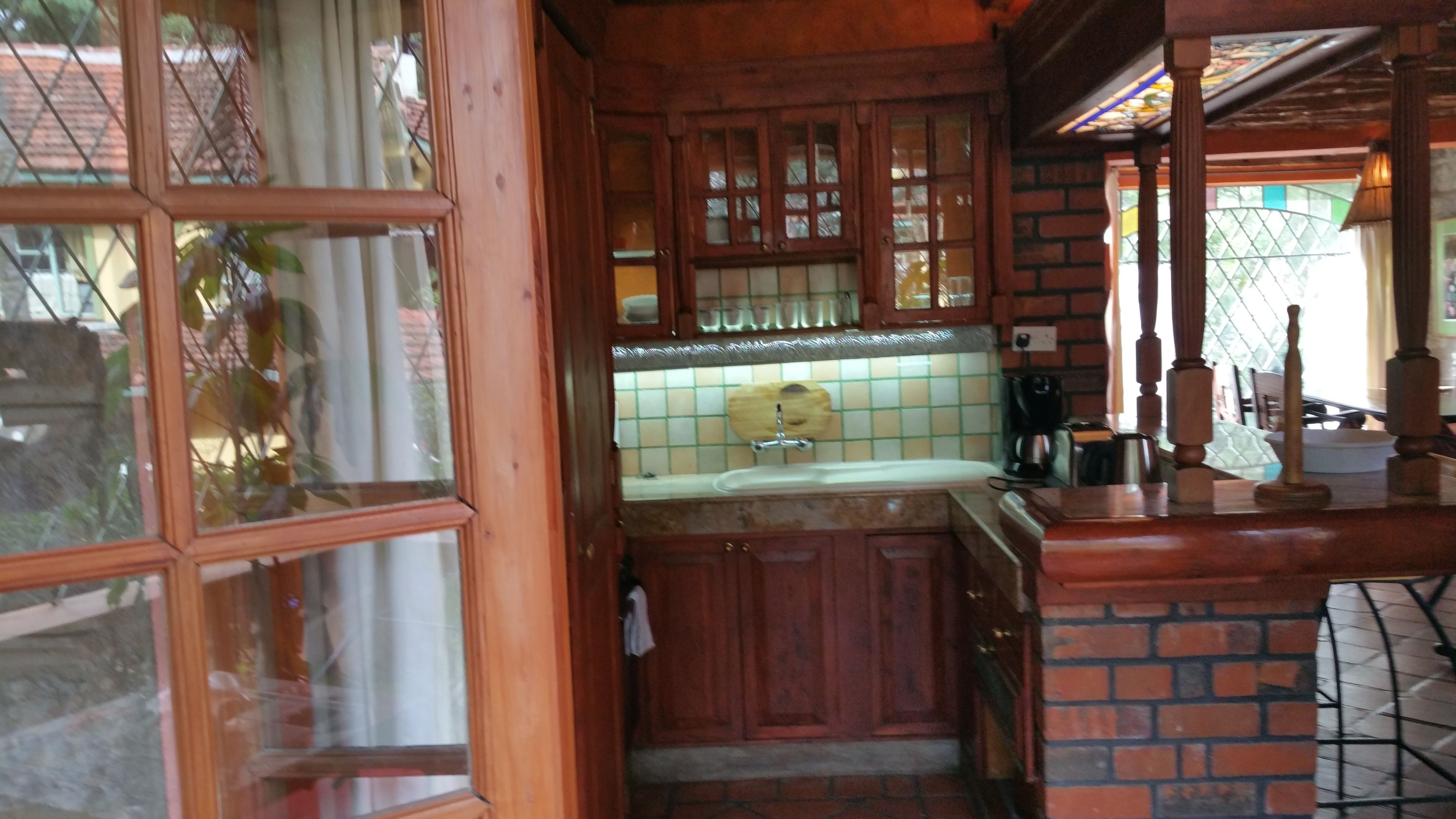 A compact kitchen with wooden cabinets, a tiled backsplash, and a small sink.