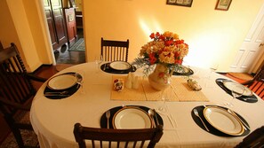 A dining table set for four with black and gold tableware, a vase of flowers, and a placemat.