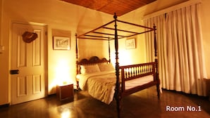 Un letto a baldacchino in una stanza con soffitto in legno e una porta con un cappotto appeso.