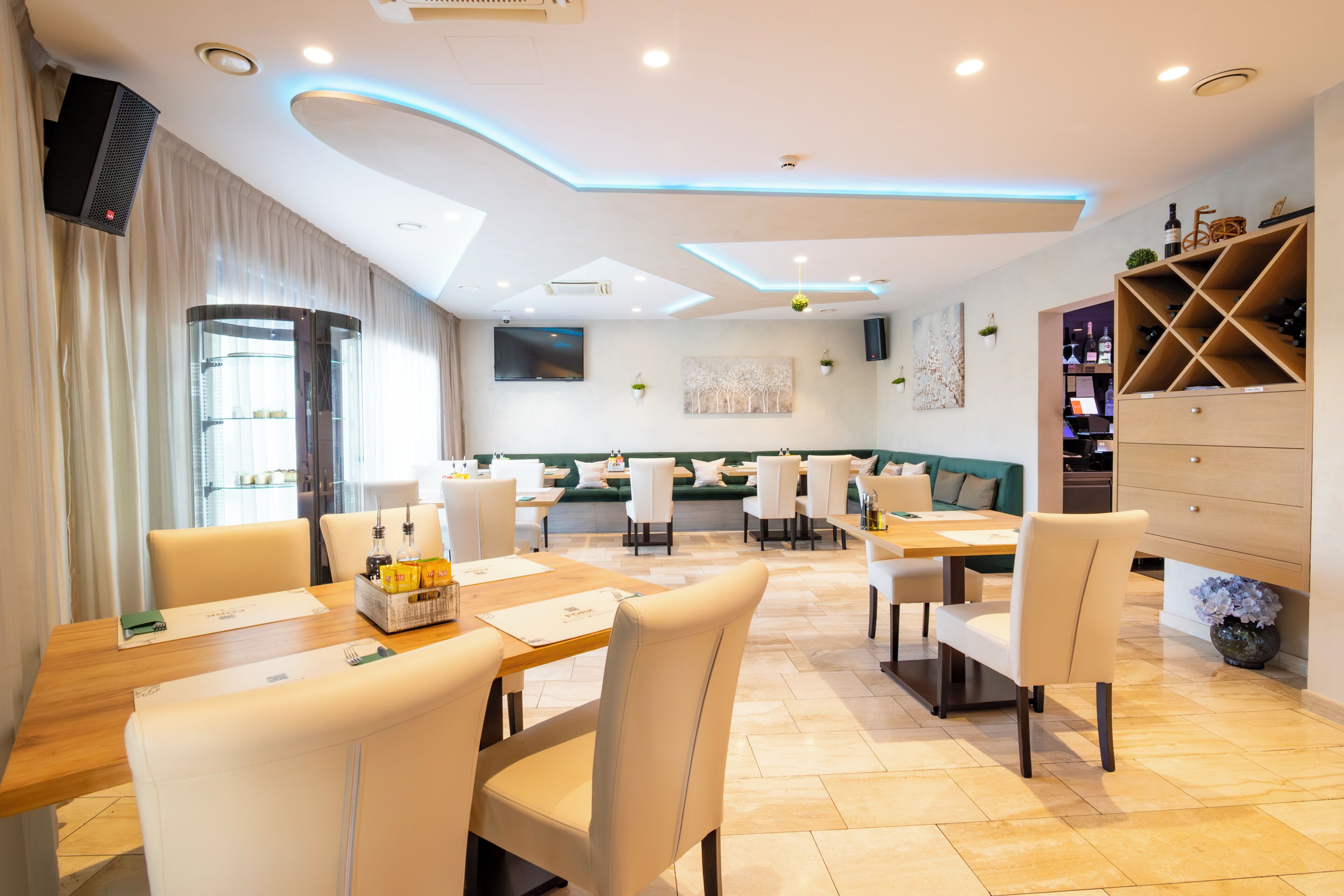 Un espace repas moderne, comprenant des tables, des chaises et un coin salon avec un canapé vert.