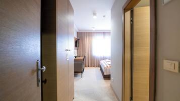 Ett hotellrum med en dörr av trä, en säng, ett skrivbord och en stol.