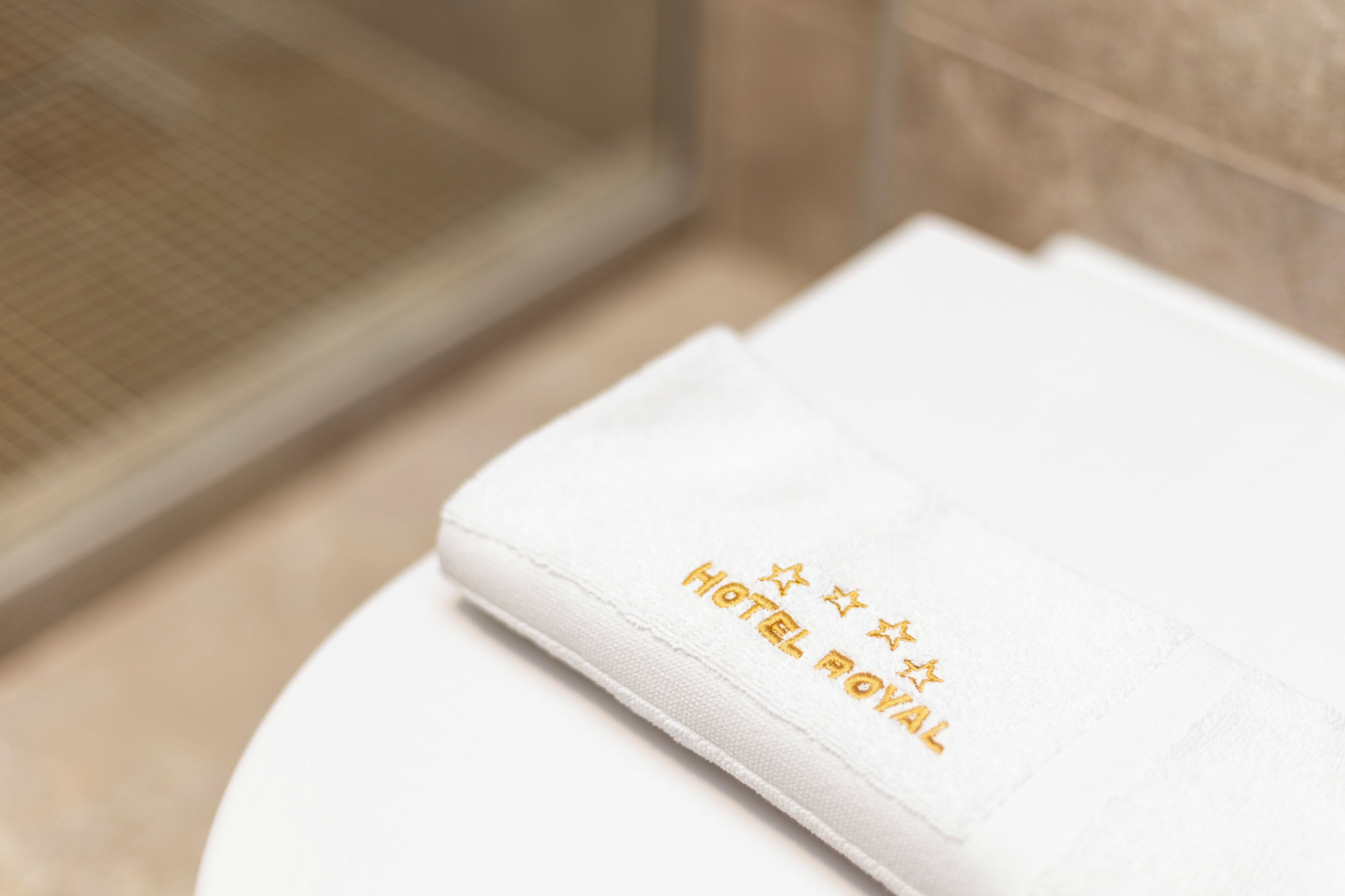 A white towel with 'HOTEL ROYAL' embroidered in gold lettering.