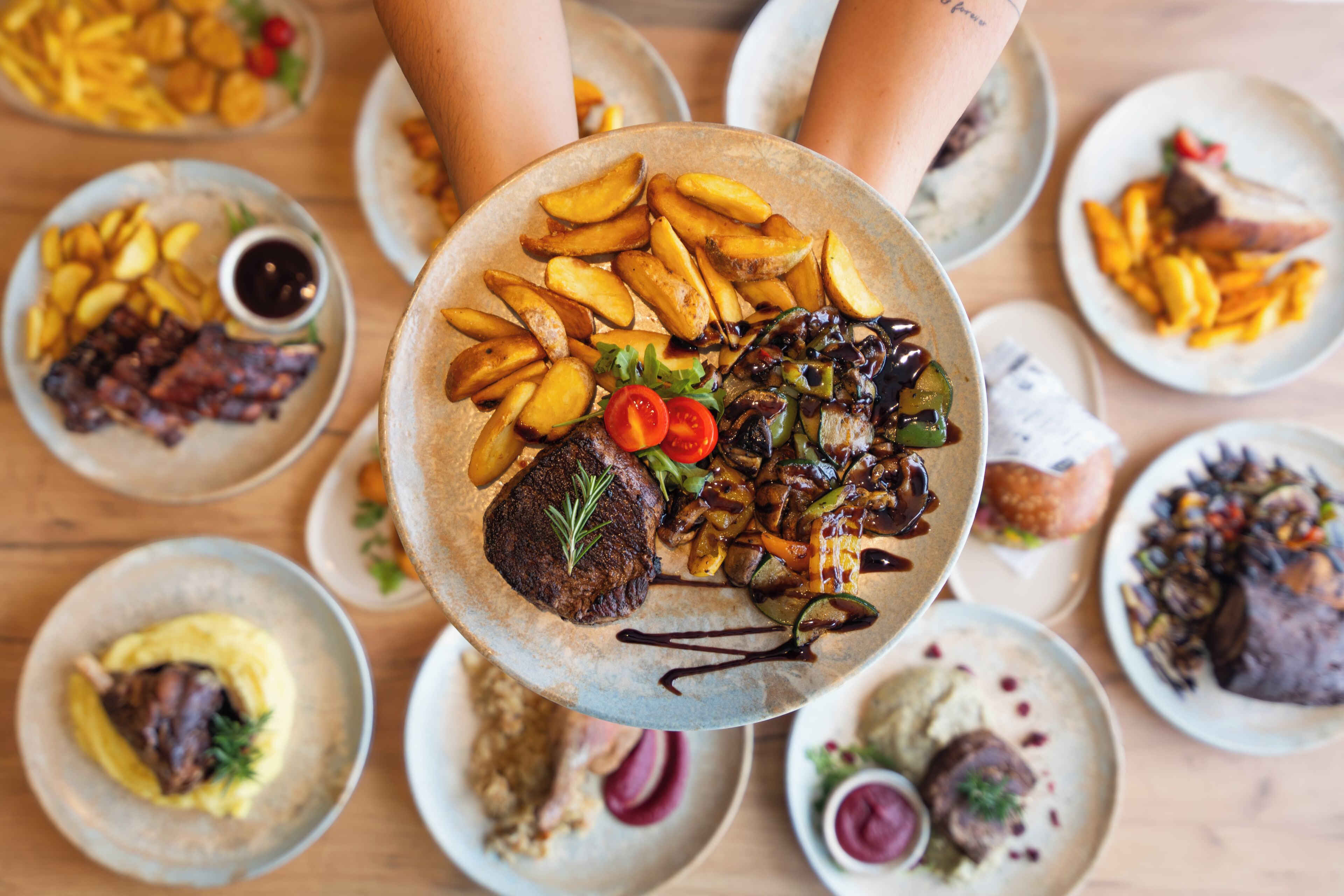 A variety of dishes on plates, including steak, fries, and vegetables.
