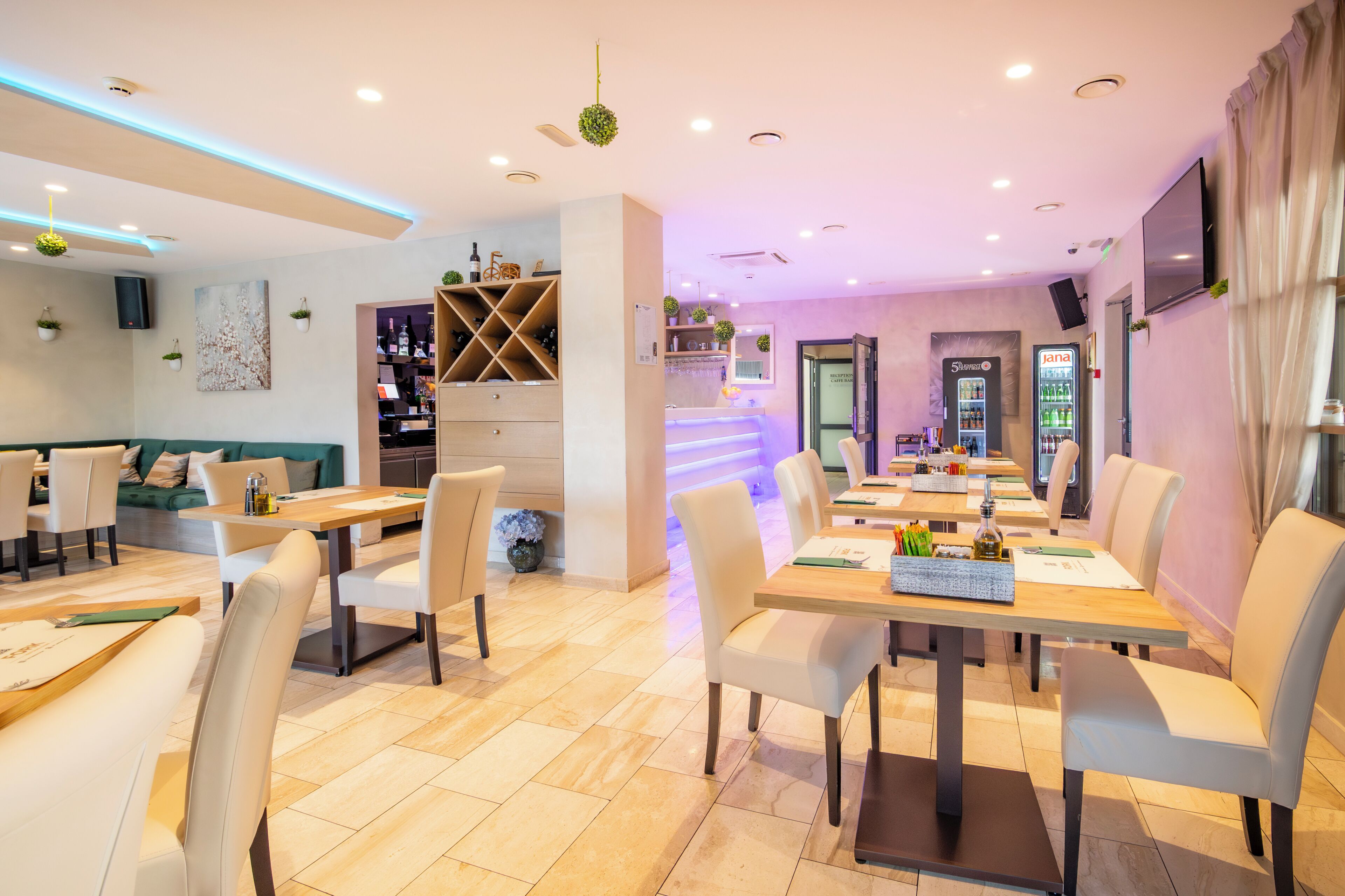 A modern restaurant with a long counter, multiple tables, and chairs.
