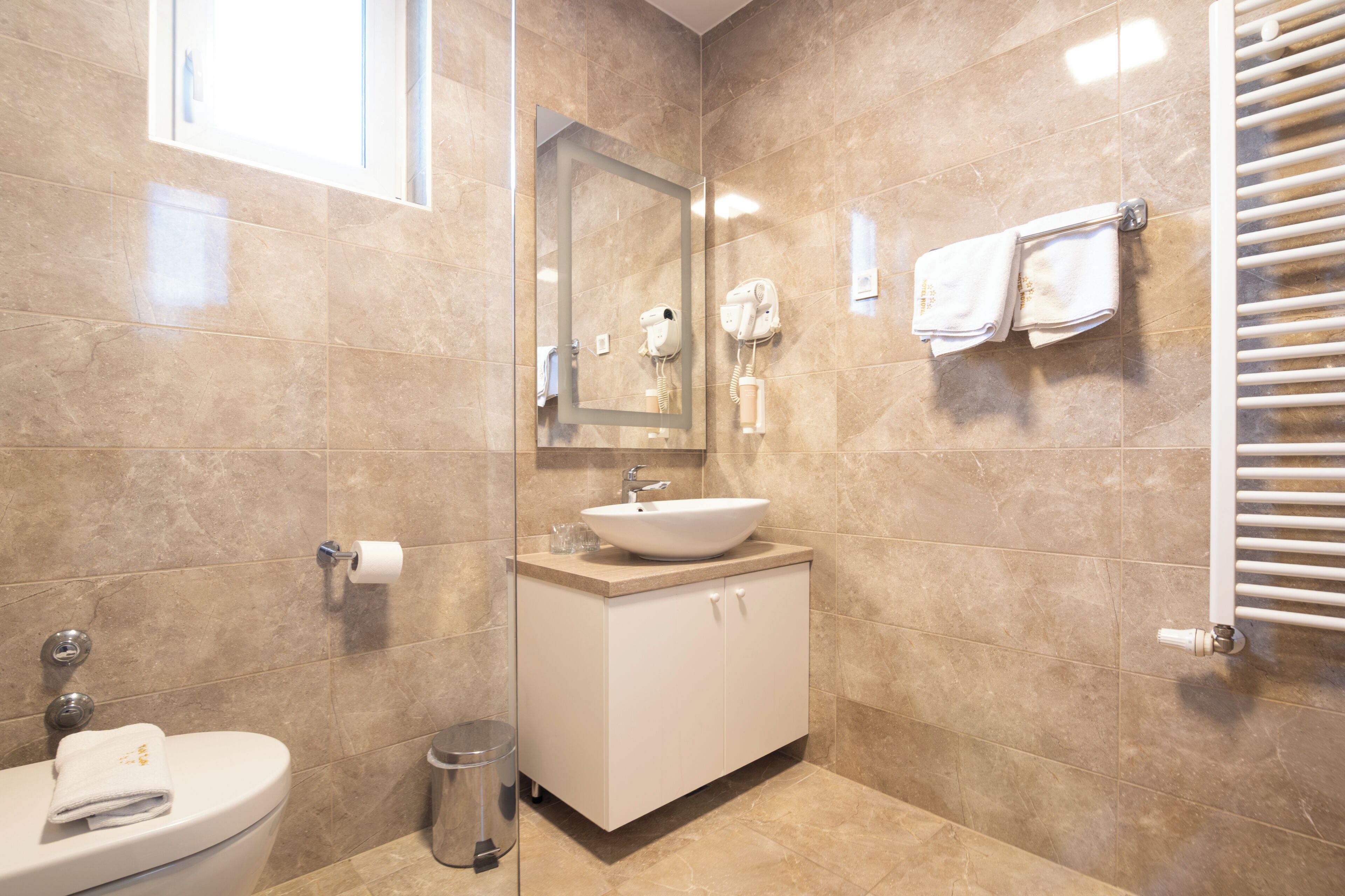 Un baño con lavamanos, espejo, toallero y un inodoro.
