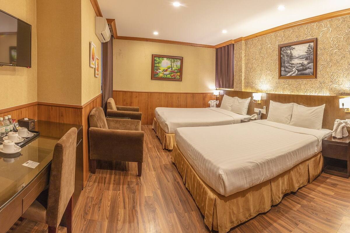 A hotel room with two beds, a desk with a chair, a TV, and a mirror.