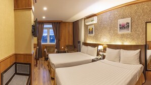 Hotelkamer met twee bedden, een televisie, bureau, stoel, verwarming en raam met gordijnen.