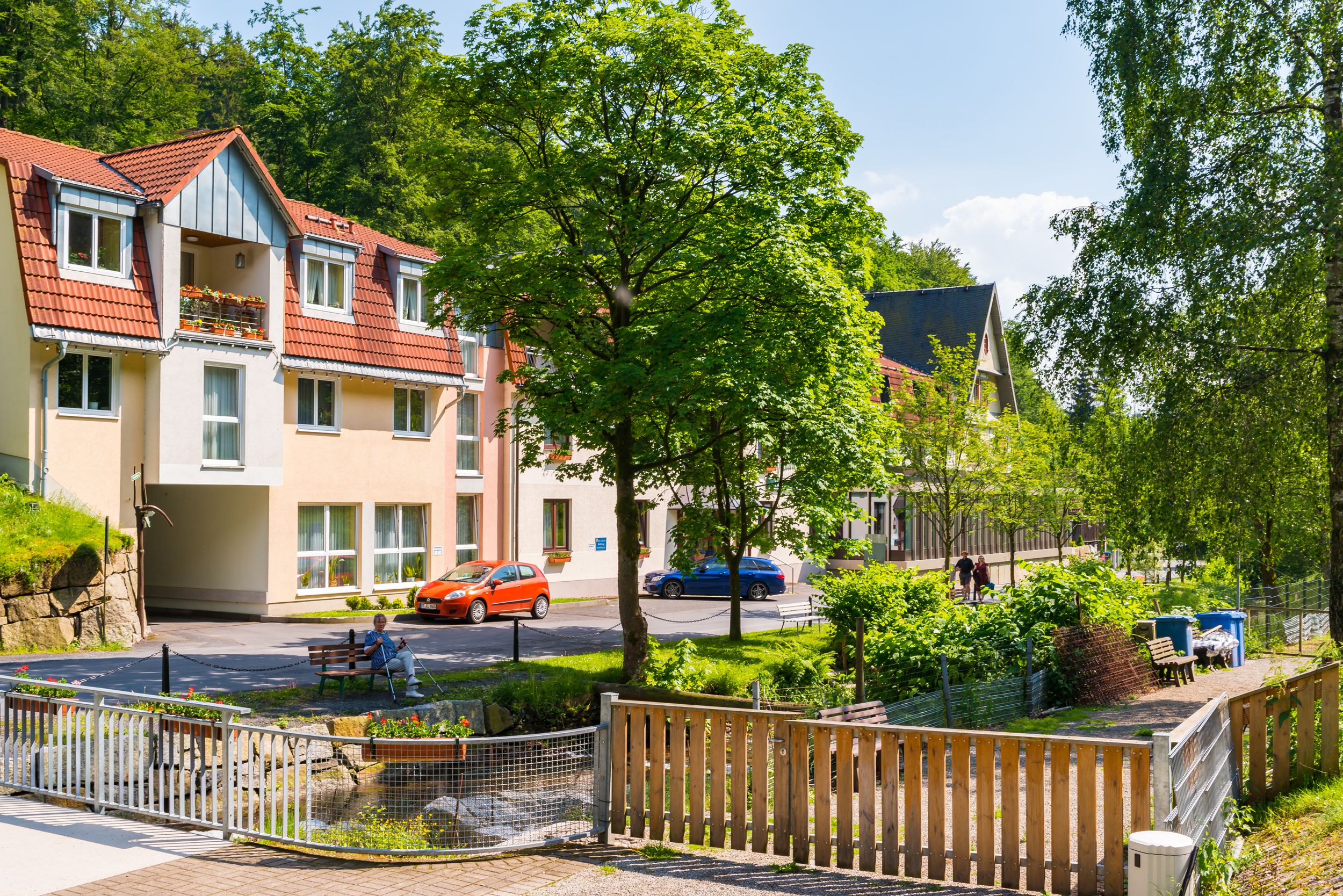 A residential area with multi-story buildings, a small garden, and a pedestrian pathway.
