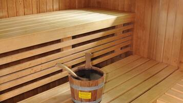 A sauna with wooden benches and a wooden bucket with a ladle.