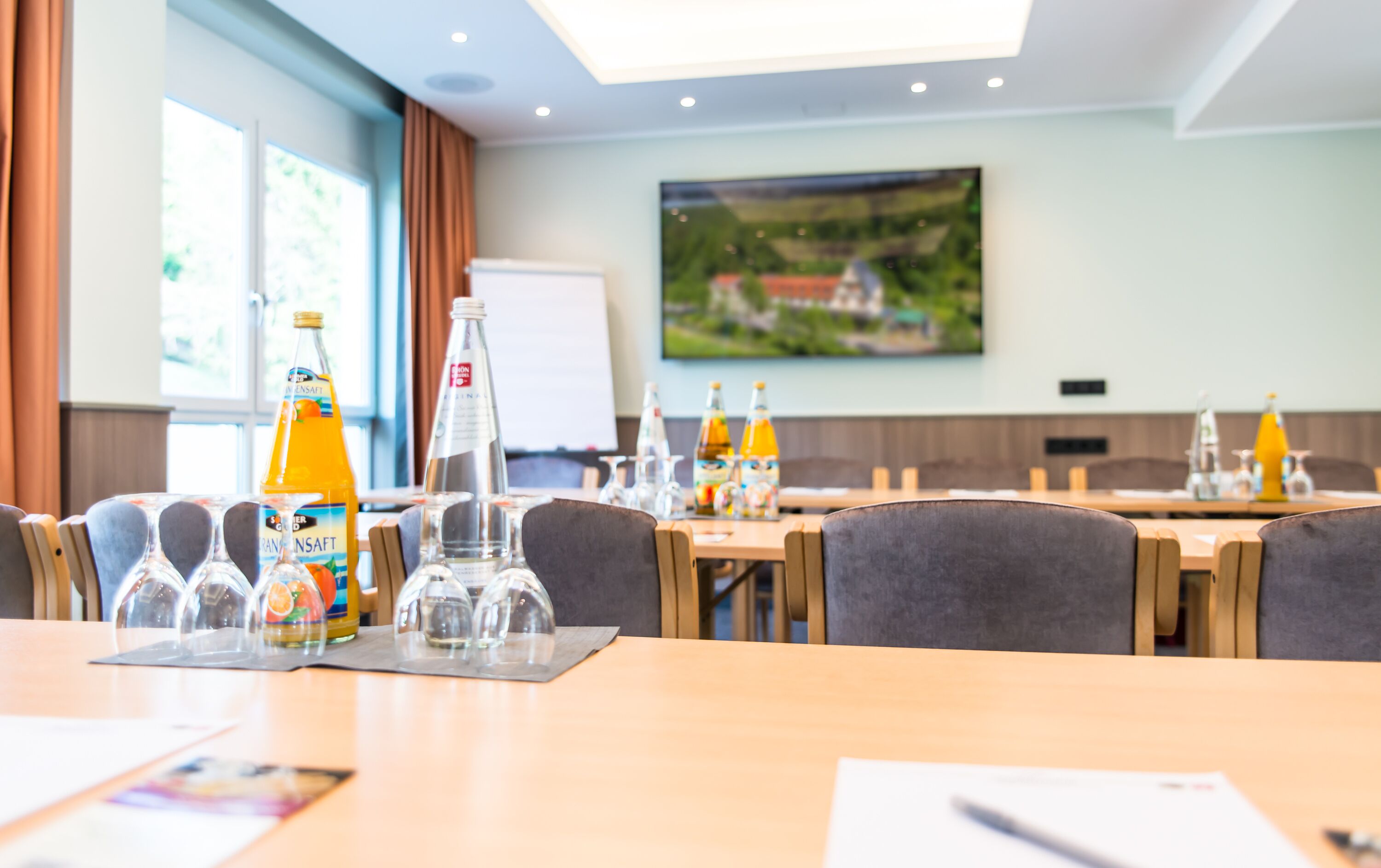 A conference room with tables, chairs, and a whiteboard. There are bottles of water and juice on the tables.