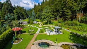 Un jardín exuberante con un estanque, zonas de estar y un pabellón.
