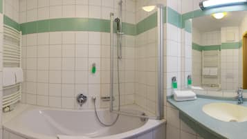 A bathroom with a bathtub, a shower, a sink, and a mirror.