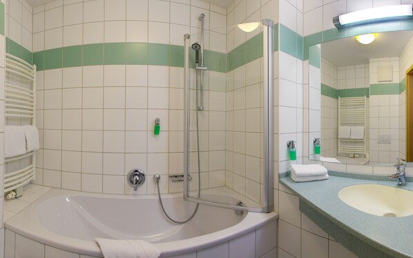 Un baño con bañera, ducha, lavamanos y espejo.