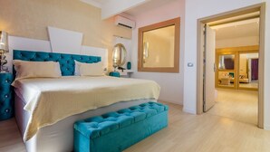 A bedroom with a large bed, a bedside table, a mirror, and a door leading to another room. - Phoenicia Luxury (Navodari)