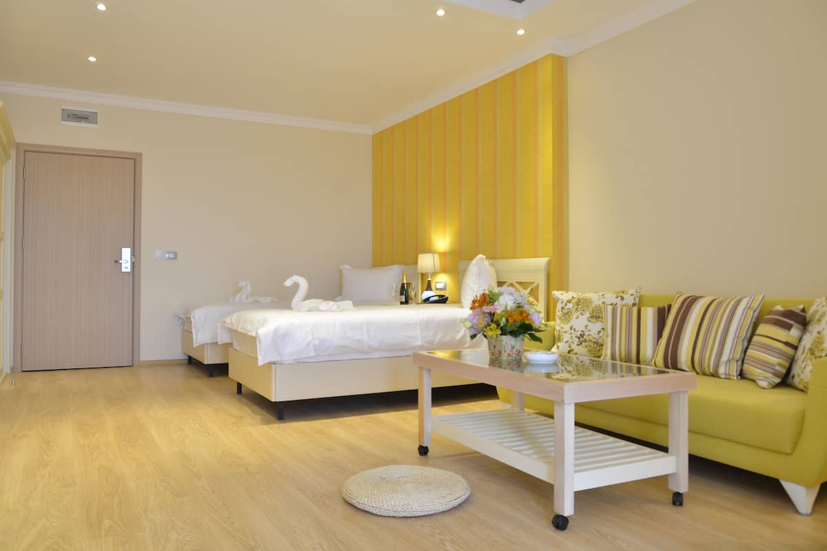 A hotel room with a bed, a sofa, a coffee table, and a door.