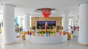 Un vestíbulo amplio con una zona de estar central, una chimenea de piedra y un candelabro moderno.