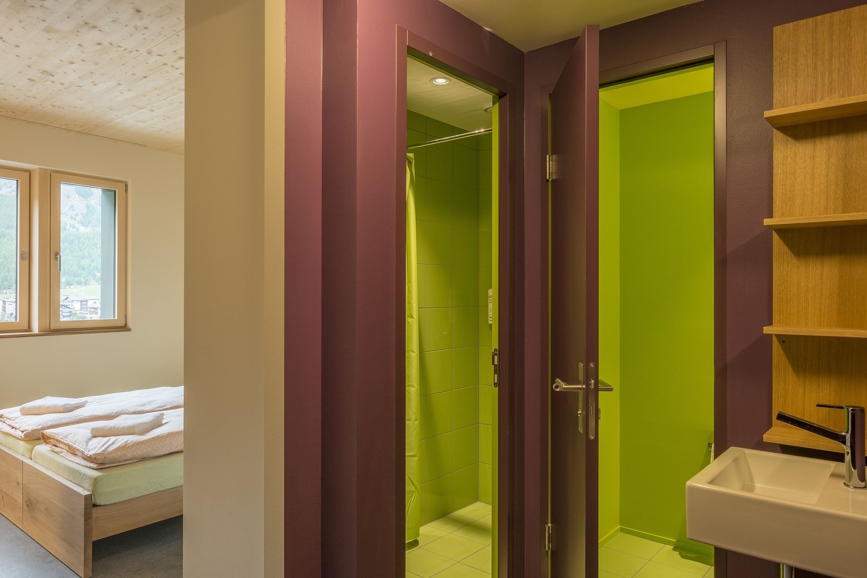 A bedroom with a bed, a bathroom with a green door, and a sink.