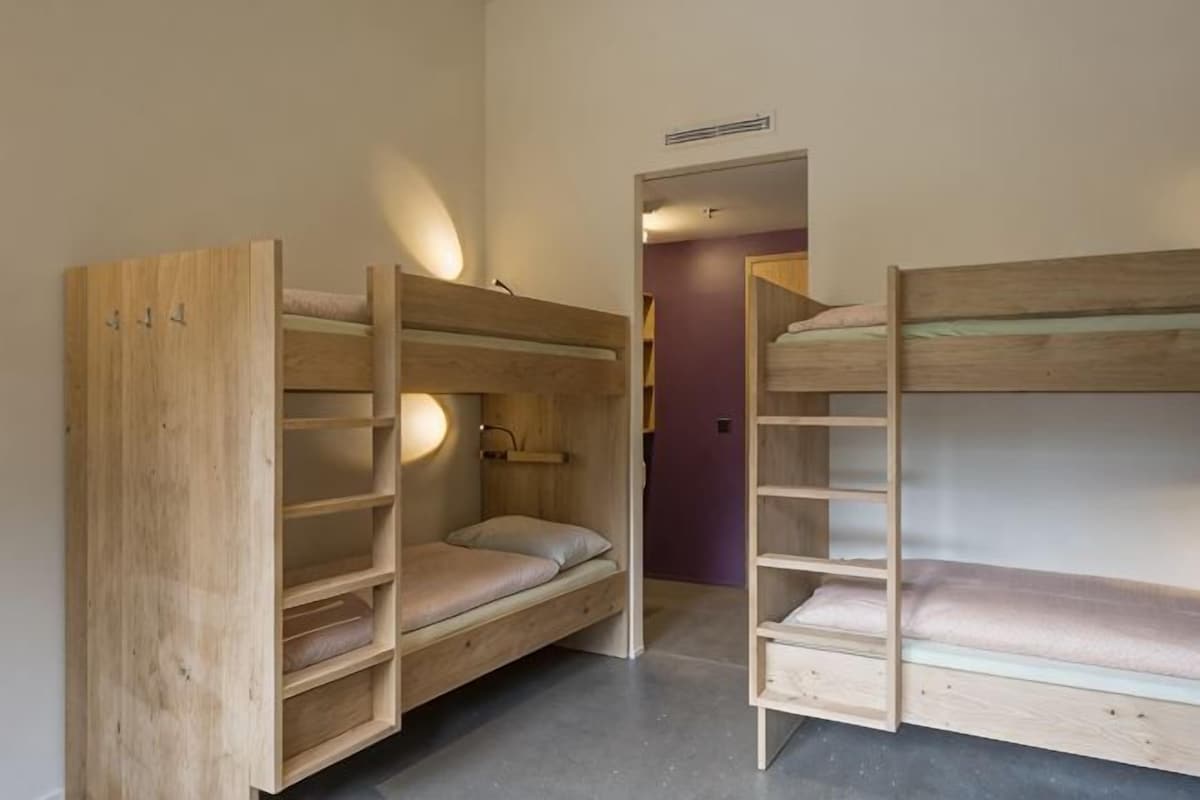 Una habitación con literas, una puerta y una lámpara.
