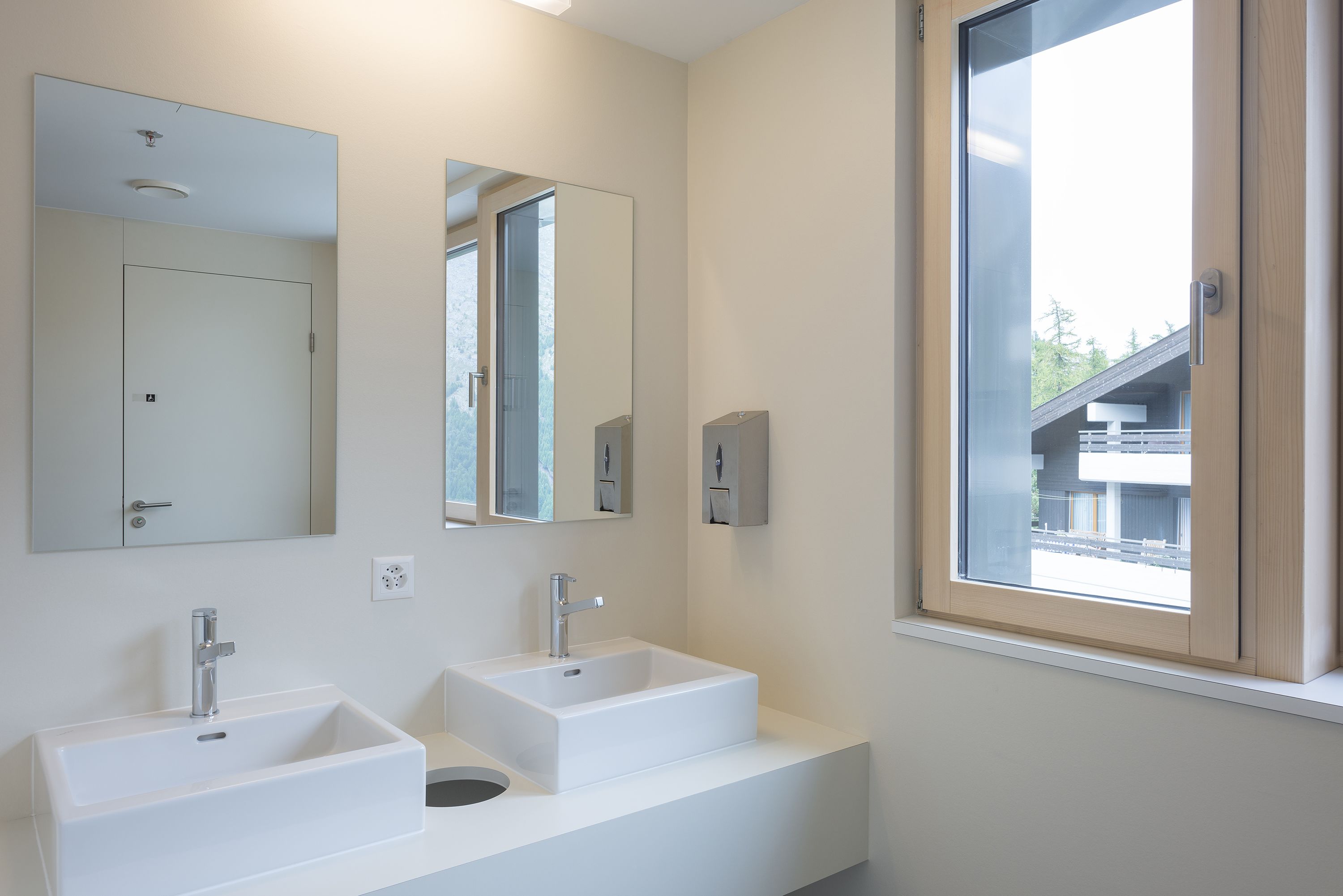 Ein modernes Badezimmer mit zwei Waschbecken, einem Spiegel und einem Fenster.