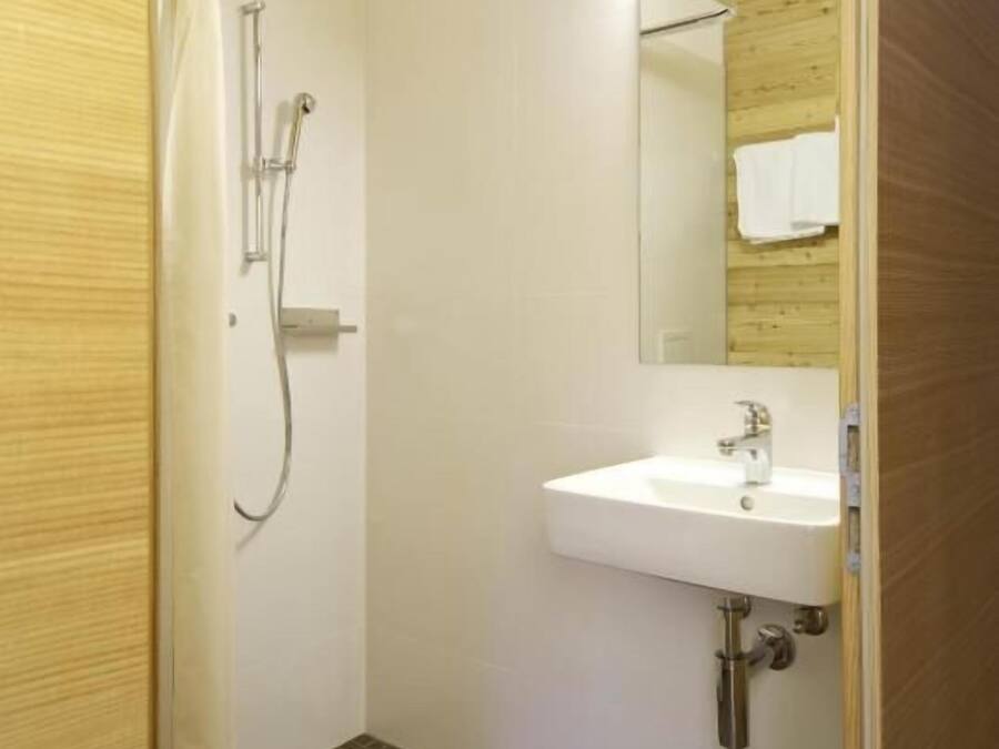 Une salle de bain avec une douche, un lavabo et un miroir.