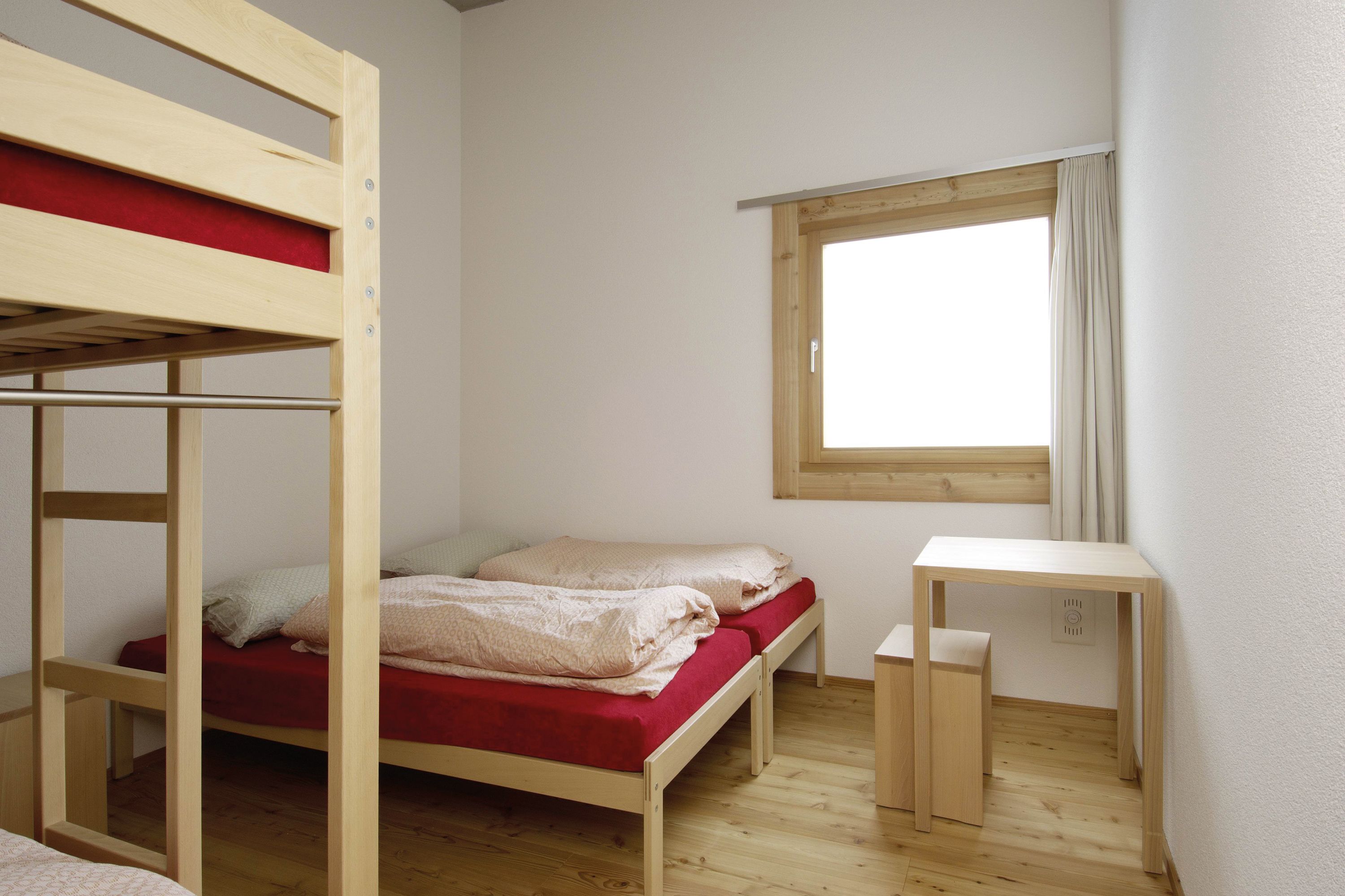 Une chambre avec un lit superposé, un bureau et une fenêtre.
