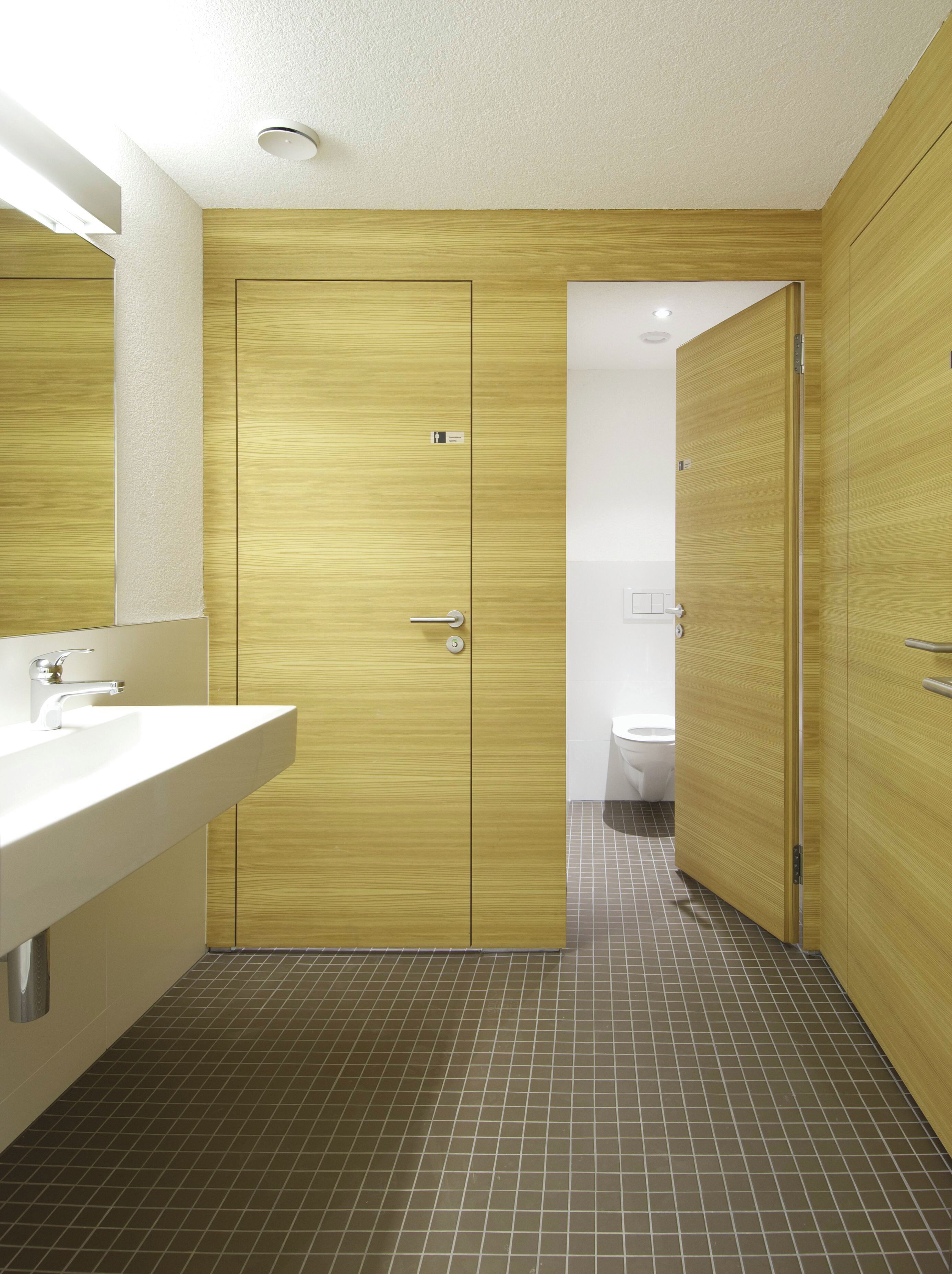 Un baño moderno con tocador de madera, lavamanos y inodoro.