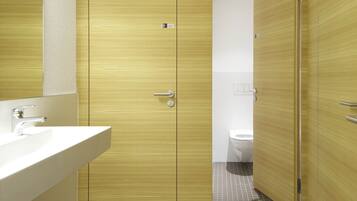 Un baño moderno con tocador de madera, lavamanos y inodoro.