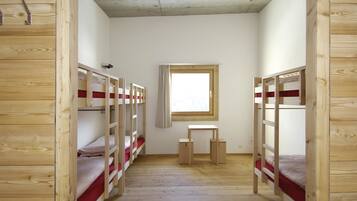 Una habitación con literas, un escritorio pequeño y una ventana.