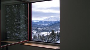 Una habitación con un amplio ventanal que ofrece vistas a montañas nevadas y a un lago.