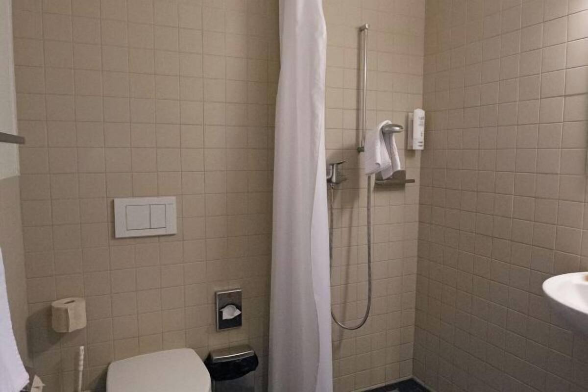 Un baño pequeño con ducha, inodoro y lavamanos.